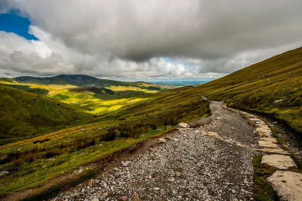 Bulutlu ve yeşil çimenli dağ manzarası