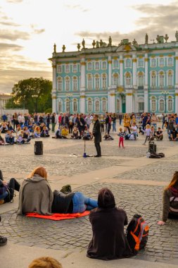 PETERSBURG, RUSSIA - 5 Ağustos 2019 'da Palace Square' de yerel bir şarkıcıyı dinleyen gençler. Arka planda kış sarayını görebilirsiniz.