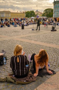 PETERSBURG, RUSSIA - 5 Ağustos 2019 Saray Meydanı 'nda yerel bir şarkıcıyı dinleyen gençler. 