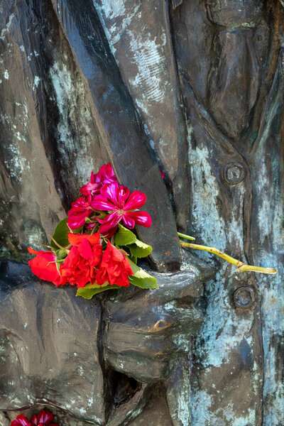 красные цветы на бронзовой статуе