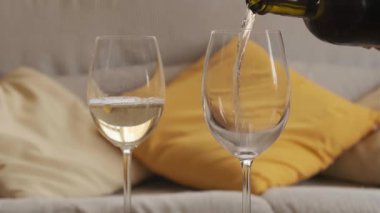 İki kadeh beyaz şarap, arka planda odaklanmamış yastıklar.