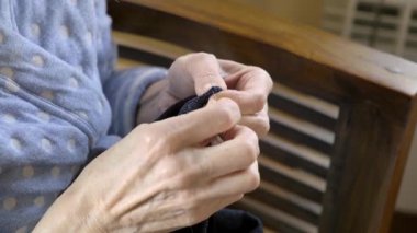 Yaşlı bir kadının ellerini dikerken yakın plan.