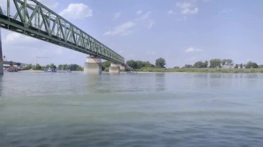 Bir demiryolu köprüsünün altındaki Tuna Nehri 'nde yol alıyoruz. Avusturya
