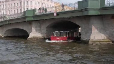 St. PETERSBURG, RUSSIA - 4 AĞUSTOS 2019: Bir yaz öğleden sonra Fontanka Nehri boyunca yelken açmak. Köprünün altından bir tekne geçiyor.