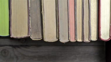 Bir adamın eli kitaplıktan bir kitap alır.