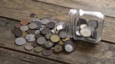 Tahta bir dönen masanın üzerinde eski paralarla dolu cam bir kavanoz.