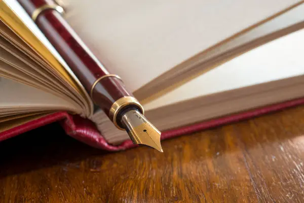 Dolma kalemin ahşap bir masada kırmızı bir kitaptaki yakınlığı..