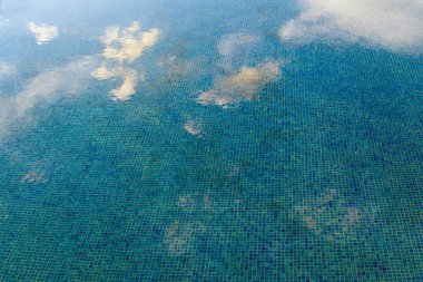 Bulutlar yüzme havuzunun suyuna yansıyor.