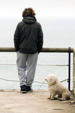 SANTANDER, İSPA - 11 Mart 2015: Genç bir adam ve köpeği bir kış sabahı denize bakıyorlar