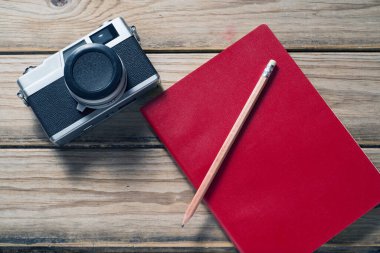 Tahta yüzey üzerinde analog fotoğraf makinesi ve defter