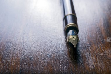 Tahta bir masanın üzerindeki dolma kalemin yakın çekimi. arka ışıklandırma