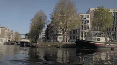 AMSTERDAM, NETHERLANDS - 10 Mayıs 2017: İlkbaharda Amsterdam kanallarında yelken. Geleneksel evler ve yüzen evler