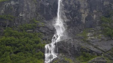 Briksdalsbreen buzuluna giden yürüyüş yolunda dağ yamaçları ve şelaleler. Gelin, Norveç.