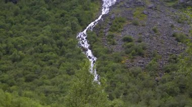 Briksdalsbreen buzuluna giden yürüyüş yolunda dağ yamaçları ve şelaleler. Gelin, Norveç.