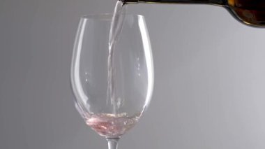 Beyaz arka planda dönen bir bardak pembe şarap.