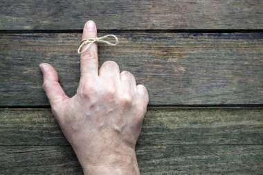 Yaşlı bir adamın işaret parmağındaki ip. Ahşap arkaplan