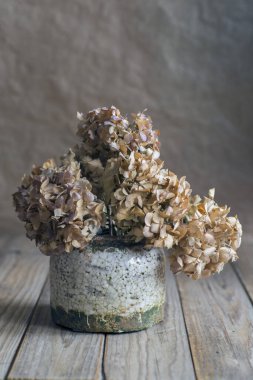 Kurutulmuş ortanca çiçekleri porselen kapta, ahşap masanın üzerinde.