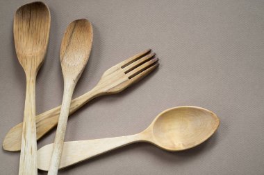 Tek renkli arka planda ahşap çatal bıçak seti yakın plan. Boşluğu kopyala