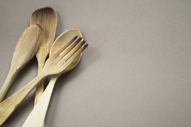 Tek renkli arka planda ahşap çatal bıçak seti yakın plan. Boşluğu kopyala