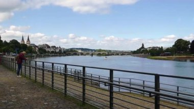 KOBLENZ - GERMANY - 11 Haziran 2019: Rhine ve Moselle nehir kenarı kesişme noktası ve arka plandaki güzel Koblenz kentinin manzarası. Nehir kenarındaki adam