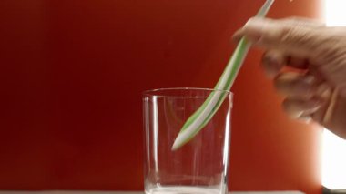 Kırmızı arka planda bir bardaktan diş fırçası almak