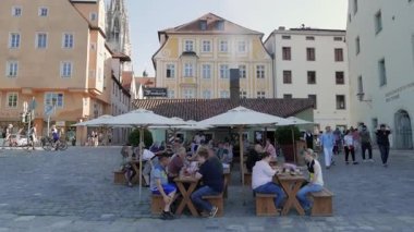 REGENSBURG, GERMANY - 13 Haziran 2019: İnsanlar Tuna Nehri kıyısındaki bir restoranın önünde oturuyorlar
