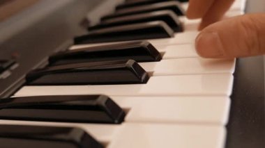 Bir adam elektronik bir orgun klavyesini çalıyor..