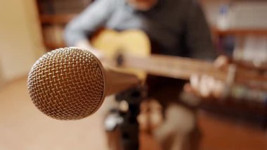 Evde müzik kaydediliyor, mikrofonun odaklı olmayan gitaristine odaklanıyor.