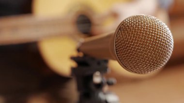 Evde müzik kaydediliyor, mikrofonun odaklı olmayan gitaristine odaklanıyor.