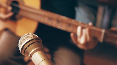Evde müzik kaydediliyor, mikrofonun odaklı olmayan gitaristine odaklanıyor.