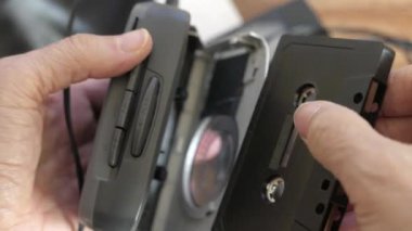 Adamın biri bir walkman 'in üzerine kaset yerleştiriyor. POV