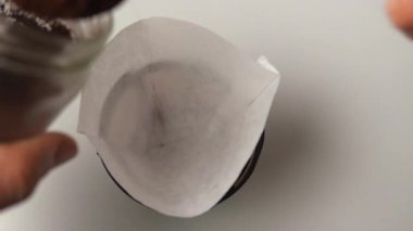 Bir adam kağıt filtreye öğütülmüş kahve döker. Kapat.