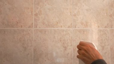 Eldivenli el fayanslı duvarı temizliyor.
