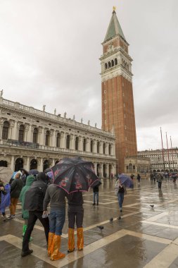 VENICE, İtalya - 30 Ekim 2018: Plaazza San Marco 'da lastik bot giyen turistler yüksek suyu bekliyorlar (acqua alta)