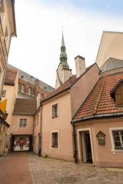 RIGA, LATVIA - 10 Haziran 2016: Riga 'nın tarihi merkezinde bir cadde. Arka planda Aziz Peter Kilisesi 'nin çan kulesi var.