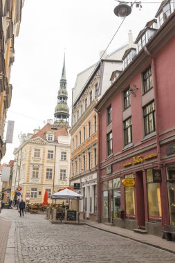 RIGA, LATVIA - 10 Haziran 2016: Riga 'nın tarihi merkezinde bir cadde. Arka planda Aziz Peter Kilisesi 'nin çan kulesi var.