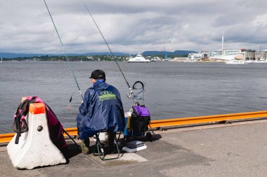 OSLO, NORway - 8 Haziran 2017: Oslo limanında bir balıkçı. Arka planda Astrup Fearnley Modern Sanat Müzesi var.