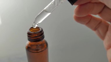 Kehribar renkli bir şişeye damlatan bir sıvı. Önplan