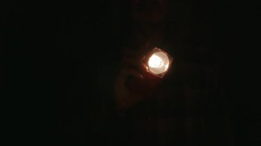 Elektrikli fenerli bir adam kameraya doğru odaklanıyor.