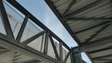 Aşağıdan görünen bir endüstriyel geçitin metal yapısında dolaşıyordu.