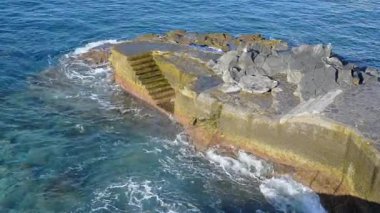 Bir kaya iskelesine çarpan dalgaların havadan görüntüsü