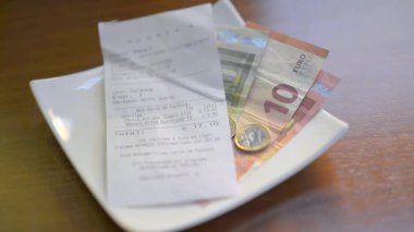 Bir erkek, bir tabaktan para toplar, ödenmiş bir faturanın iadesi. Ses
