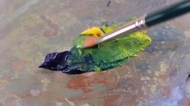 Bir ressam bir palette mavi ve sarı renkleri karıştırır