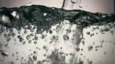 Temiz suya dökülen suyun yavaş yavaş sıçraması. Kapat.