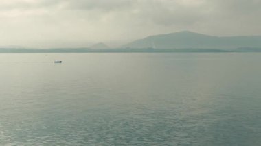 Rahatlatıcı bir kıyı manzarasının önünde yelken açan balıkçı teknesi.