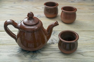 Seramik çaydanlık ve fincanlar ahşap masada.