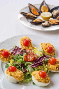 Yeşil salata ve vişneli domatesli yumurta. Arka plan midye buğulaması.