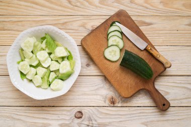 Tahta bir masada beyaz bir kasede salatalık salatası.