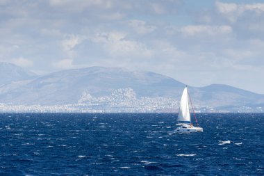 Ege Denizi 'nde yelkenli gemi. Arka planda Atina kenti