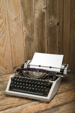 Tahta masa üzerinde beyaz kağıt sayfası olan antika bir daktilo. Eski tarz natürmort